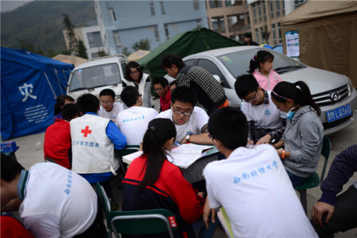 Volunteers help students study in Lushan county, Sichuan province on April 22. The county was hit by a magnitude-7.0 earthquake on April 20. Volunteers from a university in the province helped set up tents and desks, helping local students continue their studies. [Photo/Xinhua]
