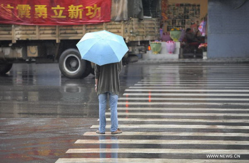 A man waits in rain to cross a crossing near Tingjin Road in Ya'an City, southwest China's Sichuan Province, April 29, 2013. According to China Meteorological Administration, Ya'an is one of the most rainy city in Sichuan in May. Experts remind on secondary disasters in Ya'an, which was hit by a 7.0-magnitude earthquake on April 20, 2013. [Photo/Xinhua]