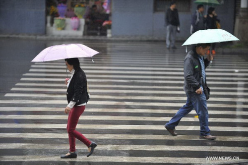 People walk in rain near Tingjin Road in Ya'an City, southwest China's Sichuan Province, April 29, 2013. According to China Meteorological Administration, Ya'an is one of the most rainy city in Sichuan in May. Experts remind on secondary disasters in Ya'an, which was hit by a 7.0-magnitude earthquake on April 20, 2013. [Photo/Xinhua]