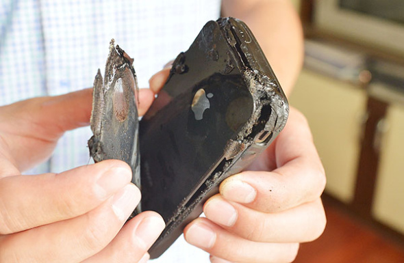 Wang Kai shows the debris of his iPhone 4, Apple's 4th-generation smartphone, after it ignited in Chongqing, on July 9, 2013. He said he was sound asleep when the phone spontaneously combusted and burnt his mat. Apple's after-sales service has been notified, saying they are investigating whether user error is to blame. [Photo by Yu Xiao/Asianewsphoto]