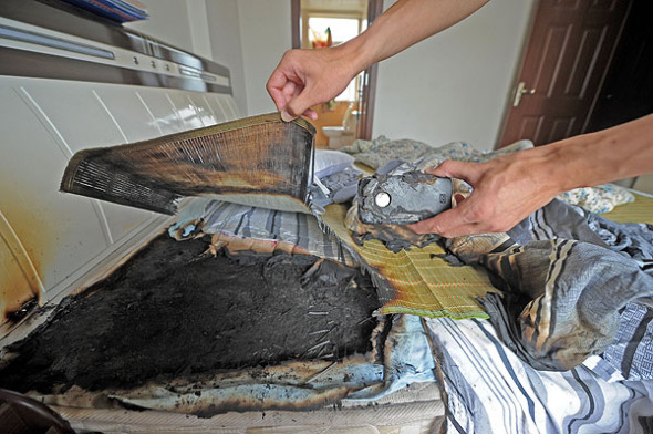 The charred remains after the iPhone 4 exploded in Wang Kai's bedroom in Chongqing, on July 9, 2013. [Photo by Yu Xiao/Asianewsphoto]