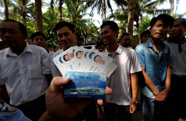 Residence permit cards are issued to residents in Sansha city, South China's Hainan province, July 17, 2013. The first batch of 10 identification cards and 68 residence permit cards are being issued to Sansha residents one year after its establishment. As China's youngest city, Sansha was officially set up last July on Yongxing Island in the South China Sea. The city administers three island groups - Xisha, Zhongsha and Nansha - and the surrounding waters in the South China Sea. [Photo/Xinhua]