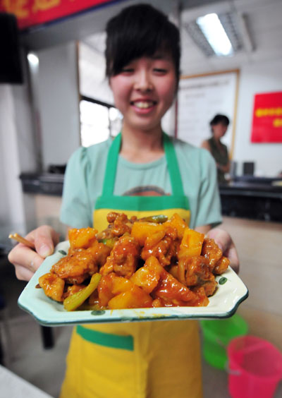 A college student presents her project from a cooking session as part of domestic service training in Fuzhou, Fujian province, on July 16, 2013. [Photo by Zhang Bin/Asianewsphoto]