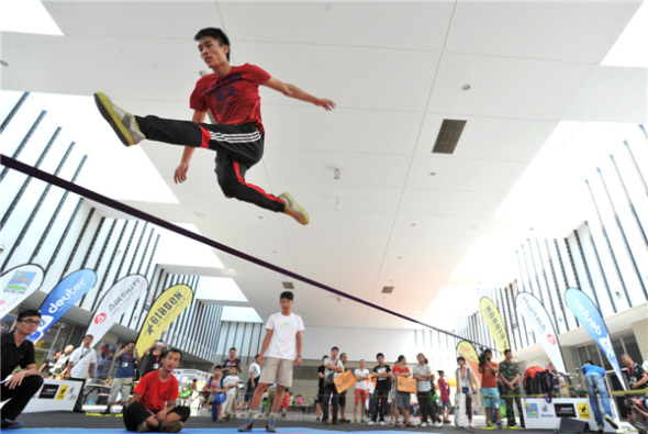 Outdoor enthusiasts jump, rotate and flip on a 5cm-wide rope at the 8th Asia Outdoor Trade Show at Nanjing International Expo Center in the capital of East China��s Jiangsu province, on July 24. Extreme outdoor sports fans turned the tight rope-walking into an extreme sport and developed a set of synchronized stunts. [You You/Asianewsphoto]
