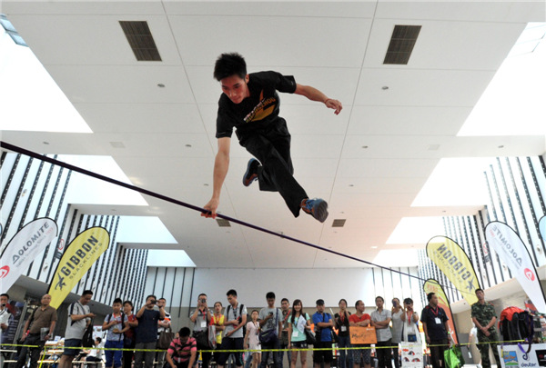 Outdoor enthusiasts jump, rotate and flip on a 5cm-wide rope at the 8th Asia Outdoor Trade Show at Nanjing International Expo Center in the capital of East China��s Jiangsu province, on July 24. Extreme outdoor sports fans turned the tight rope-walking into an extreme sport and developed a set of synchronized stunts. [You You/Asianewsphoto]