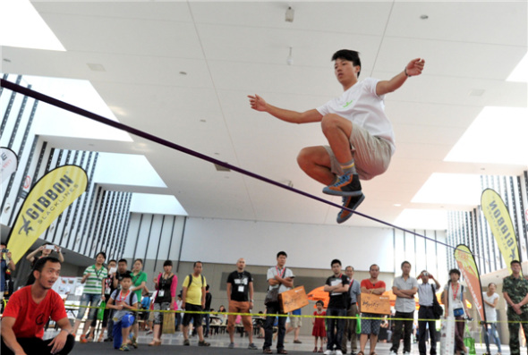 Outdoor enthusiasts jump, rotate and flip on a 5cm-wide rope at the 8th Asia Outdoor Trade Show at Nanjing International Expo Center in the capital of East China��s Jiangsu province, on July 24. Extreme outdoor sports fans turned the tight rope-walking into an extreme sport and developed a set of synchronized stunts. [You You/Asianewsphoto]