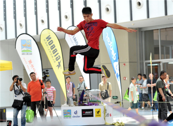 Outdoor enthusiasts jump, rotate and flip on a 5cm-wide rope at the 8th Asia Outdoor Trade Show at Nanjing International Expo Center in the capital of East China��s Jiangsu province, on July 24. Extreme outdoor sports fans turned the tight rope-walking into an extreme sport and developed a set of synchronized stunts. [You You/Asianewsphoto]