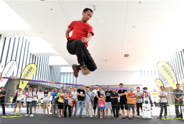 Outdoor enthusiasts jump, rotate and flip on a 5cm-wide rope at the 8th Asia Outdoor Trade Show at Nanjing International Expo Center in the capital of East China��s Jiangsu province, on July 24. Extreme outdoor sports fans turned the tight rope-walking into an extreme sport and developed a set of synchronized stunts. [You You/Asianewsphoto]