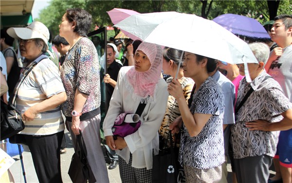 Muslims wait for food at Niujie Mosque in Beijing on Aug 8, 2013, part of activities to celebrate Eid Al-Fitr, a three-day festival that marks the end of Ramadan, Islam's holy month of fasting. [Zou Hong/Asianewsphoto]