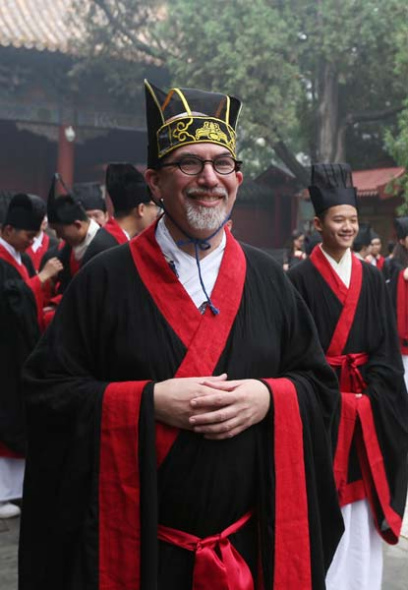 A teacher in period costume from the Han Dynasty (206BC-AD220) attends a worship ceremony at Temple of Confucius in Beijing on Aug 11, 2013. The students will study abroad next year, and the university hopes they can experience traditional culture and spread it abroad. [Photo by Lin Hui/Asianewsphoto]