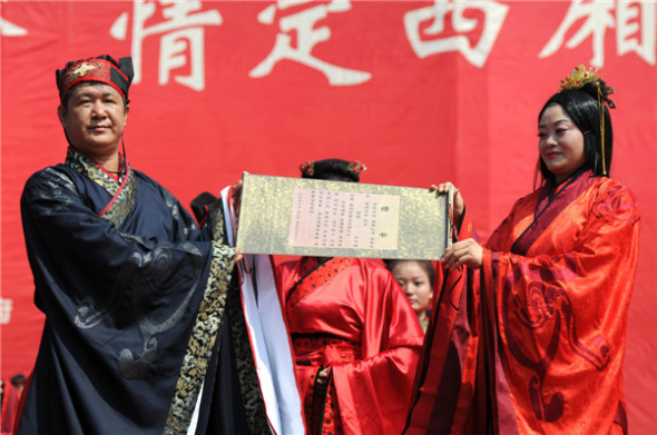Newlyweds display their marriage certificate in a Han Dynasty (206 BC-AD 220)-style wedding in Yongji, Shanxi, Aug 13, 2013. [Photo by Liu Cheng/Asianewsphoto]