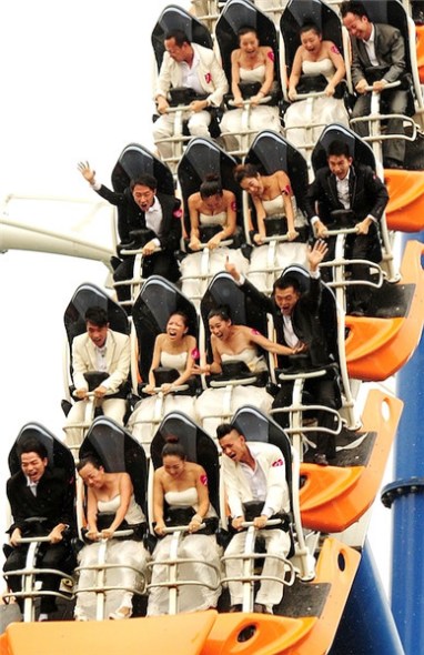 After taking the plunge with a mass wedding at a Shenzhen theme park on Tuesday, the newlyweds celebrate on a roller coaster. [Photo by Chen Wen/Asianewsphoto]