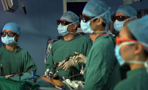 Doctors wearing 3D glasses perform a radical gastric cancer operation at Tongji Hospital in Wuhan, Central China' Hubei province, Aug 22, 2013. Gong Jianping, director of Tongji Cancer Research Institute, said of the 3D laparoscopic surgery, The operation is suitable for early and mid-term gastrointestinal cancers. And surgeries have entered the age of 3D. [Photo/Asianewsphoto]