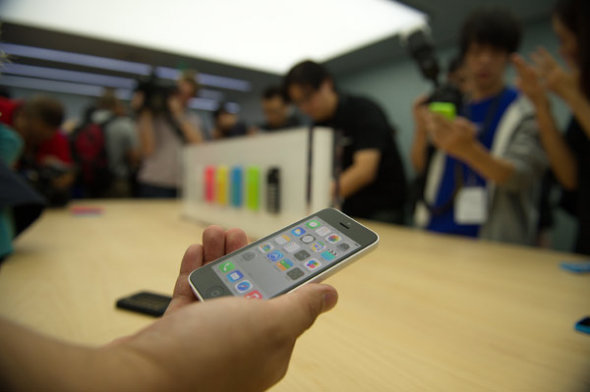 reporter holds a new iPhone 5C at a media event in Beijing, on Sept 11, 2013. [Photo by Wei Xiaochen/Asianewsphoto]