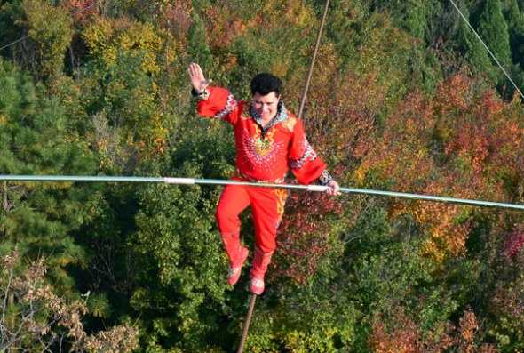 Tightrope walker Adili Wuxor walks on steel wires about 100 meters above the Huangyaguan Great Wall in Ji county, Tianjin, on Oct 17, 2013. Adili successfully finished walking above the Great Wall on his first try. [Photo/Xinhua]