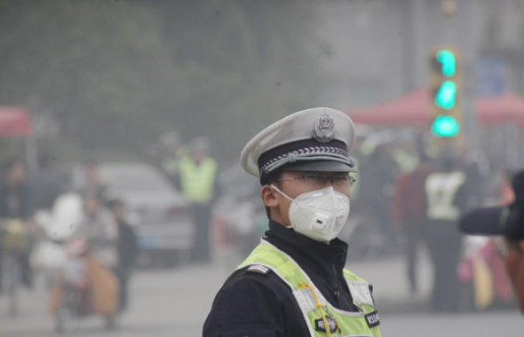 A traffic police officer directs traffic amid heavy smog in Jinan, East China's Shandong province, Oct 29. [Photo by Zheng Tao/Asianewsphoto]