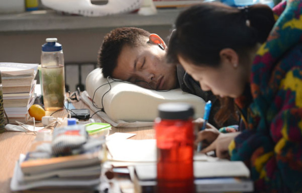 A student takes a nap while his neighbor keeps her head buried in her books in Taiyuan, Shanxi province, Oct 29, 2013. [Photo by Liu Jiang/Asianewsphoto]