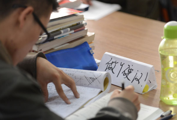 Deep in concentration, a college student in Taiyuan, Shanxi province, has a memo reminding him to be a man, Oct 29, 2013. [Photo by Liu Jiang/Asianewsphoto]