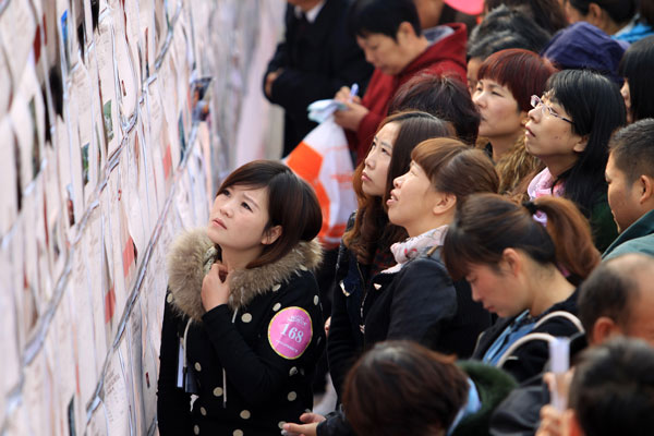 Single men and women view information about participants on a wall at a large matchmaking fair held in Xuchang, Central China's Henan province, Nov 10. More than 10,000 young people participated in the event hoping to find their true love ahead of Singles' Day, which falls on Nov 11. [Photo by Niu Yuan/Asianewsphoto]