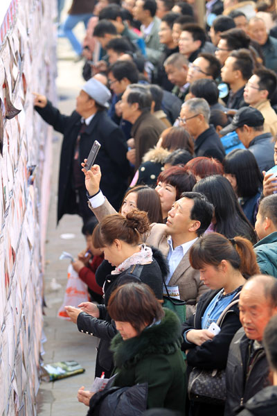 Single men and women view information about participants on a wall at a large matchmaking fair held in Xuchang, Central China's Henan province, Nov 10. [Photo by Niu Yuan/Asianewsphoto]