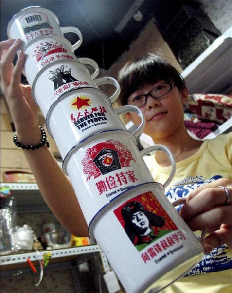 File photo taken in July of 2010 shows a girl showing porcelain enamel cups with quotations on them popular from the 1950s to the 1970s in China in a marketplace in Jinan, capital of East China's Shandong province. [Photo/Xinhua]