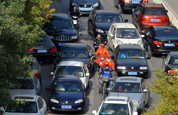 People ride through parked and moving vehicles in Xicheng district, Beijing, Nov 15, 2013. [Photo/Xinhua]