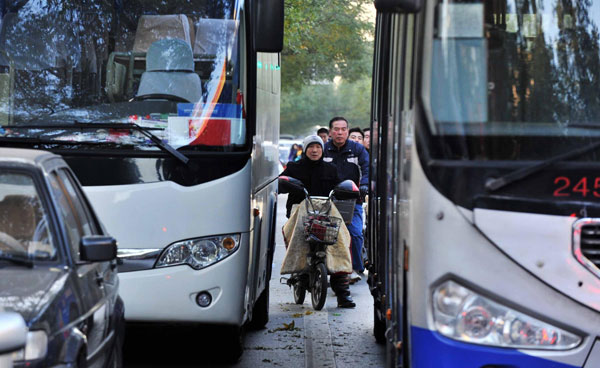 Pedestrians and bikes move through the street as bicycle lanes are occupied by cars, Nov 14, 2013. [Photo/Xinhua]