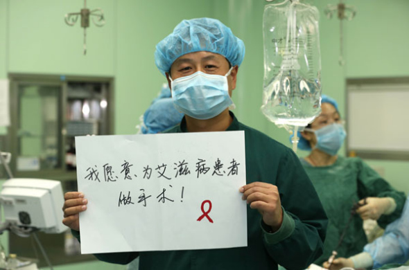 A doctor in Xiangyang, Hubei province, hold up a sign that reads, I'd like to operate on HIV patients, Nov 28, 2013. [Photo by Chen Wen/Asianewsphoto]