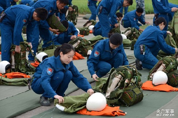 The picture shows that female pilots prepare parachutes before boarding the plane. (mil.cnr.cn/Shen Ling)