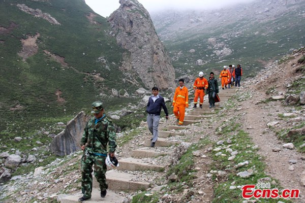 People walk downhill on the Maya Snow Mountain in northwest China's Gansu Province on Sunday, July 20, 2014. Five tourists were saved by a search and rescue team Sunday after being lost and stranded on the mountain for more than 20 hours. [Photo: China News Service/Li Yonglin]