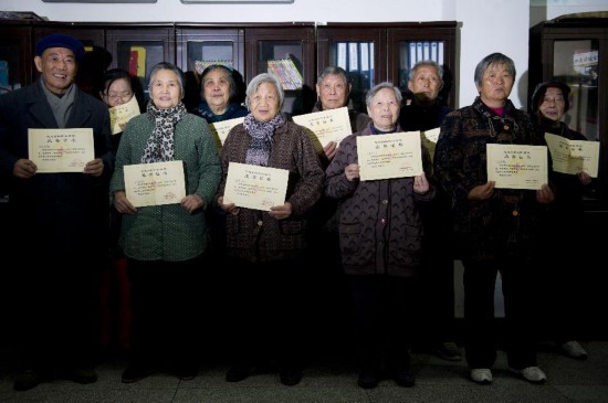 A group of elderly people pose for a photograph holding certificates saying that they agree to donate their bodies to medical research in Anhui province on Dec 2, 2014. The group belonged to a geological prospecting team before retiring. Eighteen members of the team have signed up to donate their bodies to science. [Photo:Xinhua/Du Yu]