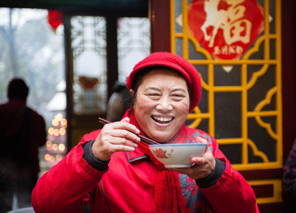 A woman enjoys a bowl of La Ba porridge in Nanjing, Jiangsu province on Jan 8, 2014. [Photo/Xinhua]