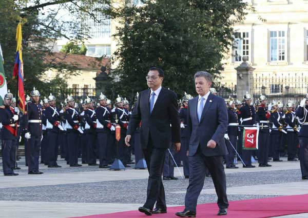 Premier Li Keqiang, left, accompanied by Colombian President Juan Manuel Santos Caldern, reviews the guards of honor at the Presidential Palace after Li's arrival in capital Bogota on May 21, 2015. (Photo/english.gov.cn)