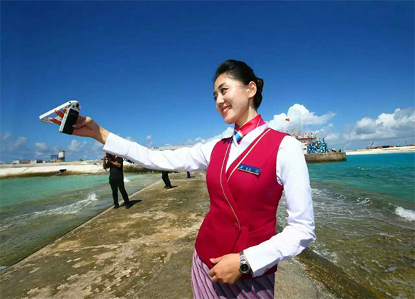 A stewardess takes a selfie after a Chinese aircraft lands on the newly constructed runway at Yongshu Jiao in China's Nansha Islands during a test flight on Jan 6. (Photo/Xinhua)