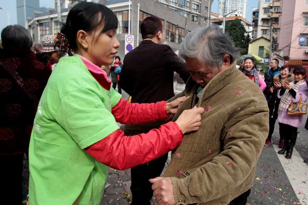 A student volunteer helps an old woman try on a jacket donated by local resident in Liuzhou city, South China's Guangxi Zhuang autonomous region, Jan 30, 2016. (Photo by Qing Yaolin/China Daily)