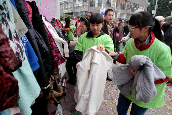 Student volunteers fold donated clothing from local residents in front of a Wall of Kindness in Liuzhou city, South China's Guangxi Zhuang autonomous region, Jan 30, 2016. (Photo by Qing Yaolin/China Daily)