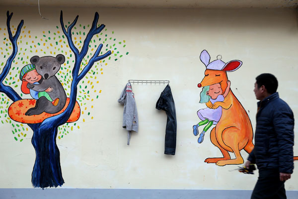 A local resident passes by the cartoon-decorated Wall of Kindness in Zhengzhou city, Central China's Henan province, Feb 2, 2016. (Photo by Hou Jianxun/China Daily)