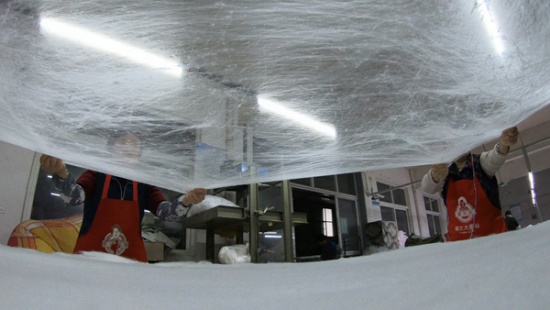 Craftsmen make silk quilts at a factory in Tongxiang, Zhejiang province. Photo by Gao Erqiang / China Daily