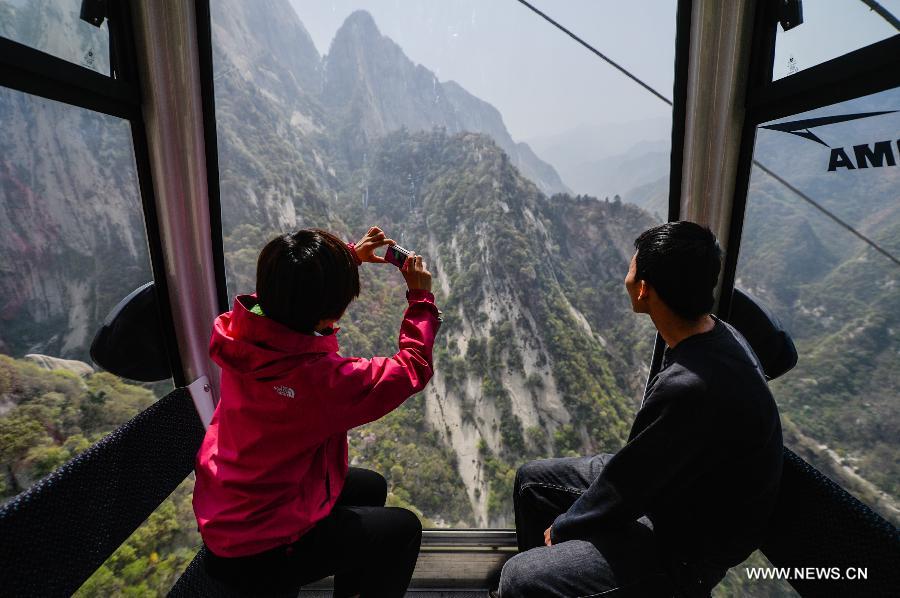 
Visitors view the scenery of Mount Huashan in a cable car at Huashan Mountain Scenic Area in Xi\'an, capital of northwest China\'s Shaanxi Province, April 1, 2013.The 4,211-meter cableway to the west peak of Mount Huashan was put into trial operation on Monday after four years\' construction. There are two cableways on Mount Huashan so far, one to the west peak and the other to the north peak. (Xinhua/Ding Haitao) 