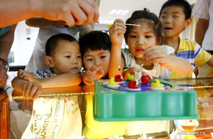 
Children play a fishing toy at an old toy exhibition in east China\'s  Shanghai, July 2, 2014. The toys presented on the exhibition, from the  collections of 18 collectors, remind visitors born in the 1970s and the 1980s of  their childhood. (Xinhua/Fang Zhe) 