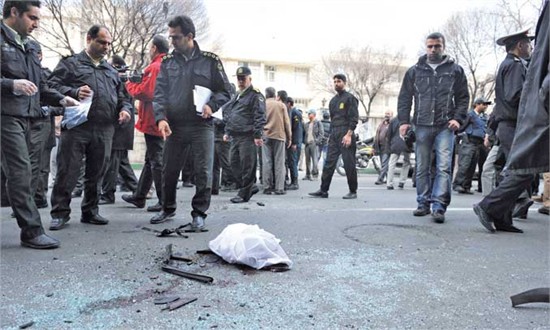 Iranian security forces inspect the site where a magnetic bomb attached to a car by a motorcyclist exploded outside a university in Tehran Wednesday, killing a scientist and injuring two other people.,