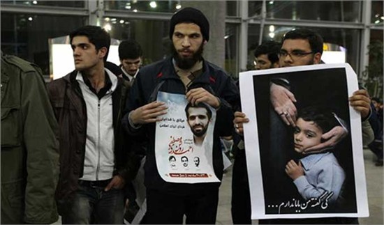 Iranian students hold photos of assassinated nuclear scientist Mostafa Ahmadi-Roshan and his son as they protest at the Imam Khomeini Airport in Tehran Sunday during the arrival of the team of International Atomic Energy Agency inspectors. Photo: AFP