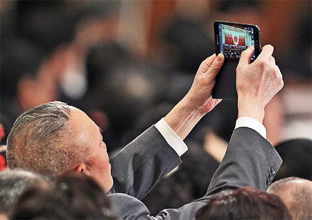 A deputy to the National People's Congress takes a picture during the second plenary meeting of the Fifth Session of the 11th NPC at the Great Hall of the People in Beijing on Thursday morning. [Wu Zhiyi / China Daily]