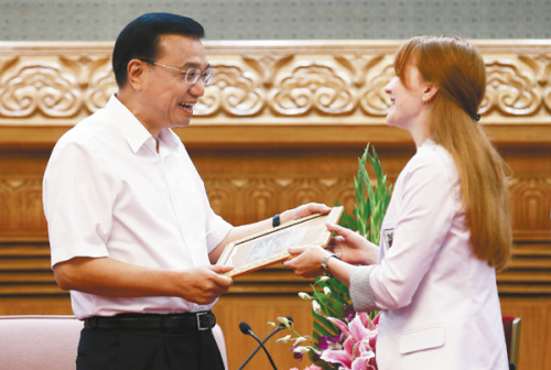 Vice-Premier Li Keqiang receives a gift from a student representative of Moscow State University at the Great Hall of the People on Aug 24. [Photo by Du Yang/China News service]