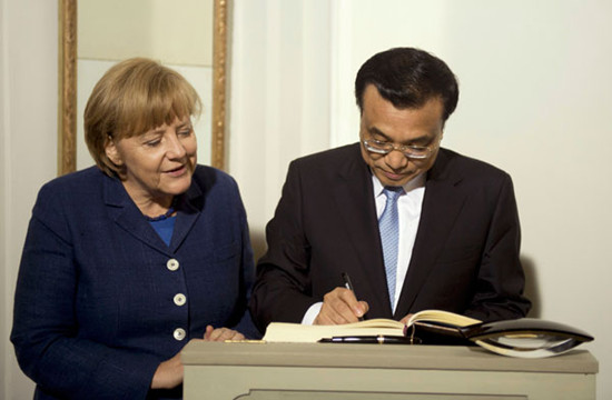 German Chancellor Angela Merkel watches Premier Li Keqiang sign the guest book on his arrival for a dinner at the German government's Meseberg Palace in Meseberg some 60 km north of Berlin, on Sunday. Odd Andersen / Reuters