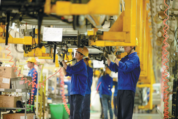 Employees at an automobile factory fine-tune a vehicle in Qingdao, Shandong province. China's GDP grew by 7.3 percent in the third quarter of 2014. [Provided to China Daily]