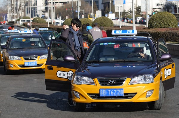 Taxis near Beijing Railway Station take passengers on Friday. Last Thursday, the Ministry of Transport has prohibited private cars from taking passengers for profit in response to strikes by taxi drivers in some cities. Wang Zhuangfei/CHINA DAILY