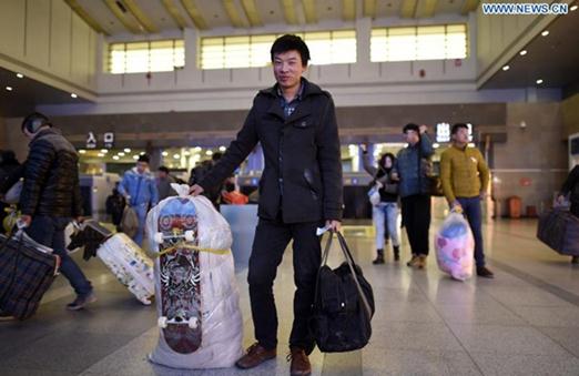 A man presents a skateboard he bought for his son before boarding his train home at the railway station of Hangzhou, capital of east China's Zhejiang province, Feb 3, 2015.The 40-day travel frenzy known as Chunyun, the hectic period surrounding Chinese New Year, or Spring Festival, which falls this year on Feb 19, will begin on Feb 4 and last until March 16. [Photo/Xinhua]