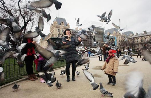 Chinese tourists play in front of Notre-Dame de Paris. Data suggest a record number of them chose to travel abroad during this year's Spring Festival. Provided to China Daily   
