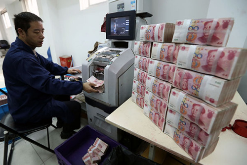 A bank employee prepares bank notes. The State Council moved to scrap a rule that caps lending by commercial banks at 75 percent of their deposits, a measure that will increase the supply of cash in the financial system. (Photo/China Daily)